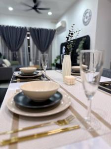a dining room table with plates and glasses on it at Wind Serenity & FOC Netflix Access Country Garden Danga Bay 3BR # 6-11 pax by Minshuku in Johor Bahru