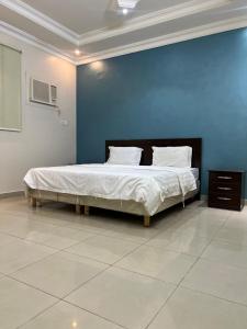 a bedroom with a large bed with a blue wall at Najmat Sabbabah Furnished Units in Hail