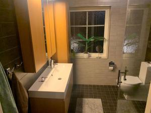 een badkamer met een wastafel, een toilet en een raam bij Guest house or Loft with summer Pool in Bro