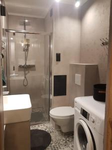 a bathroom with a shower and a toilet and a washing machine at Apartament Chrobry in Kętrzyn