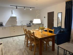 a kitchen and dining room with a wooden table and chairs at Apartamenty Prima in Dziwnówek