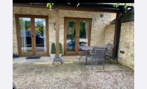 a patio with a table and chairs in front of a house at Little Kent End Cottage in Ashton Keynes