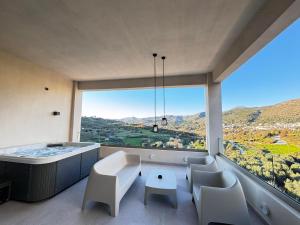 una camera con vasca, sedie e una grande finestra di Panorama Luxury Suites a Spílion