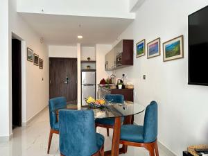 a kitchen and dining room with a glass table and blue chairs at Ocean Breeze Hotel Residencies BritLanka Apartments Negombo in Negombo