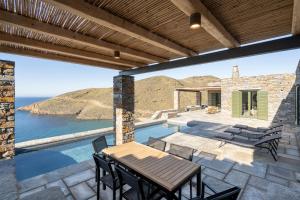 a patio with a table and chairs and the ocean at Triad Villas in Ioulis