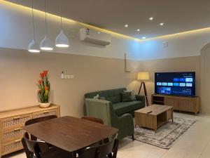 ein Wohnzimmer mit einem Sofa, einem Tisch und einem TV in der Unterkunft بوتيك هاوس بتصاميم مميزة وأنيقة in Ha'il