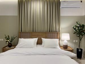 1 dormitorio con 1 cama grande con sábanas y almohadas blancas en بوتيك هاوس بتصاميم مميزة وأنيقة, en Hail
