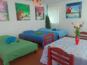 two beds and two tables in a room with paintings at Amazon Nativo Lodge in San Pedro