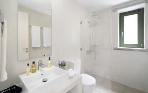 a white bathroom with a sink and a shower at Triad Villas in Ioulis +29 photos