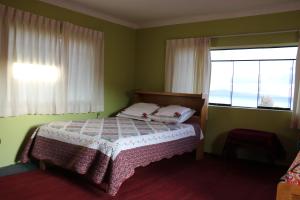 1 dormitorio con cama y ventana grande en SUNSET Lodge Amantani, en Ocosuyo