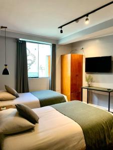 a hotel room with two beds and a flat screen tv at Casa Encuentro San Blas in Cusco