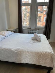 a bed with two towels on it in a room with two windows at Flat brussels center in Brussels