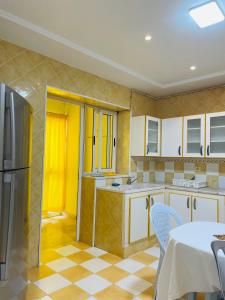 a kitchen with white cabinets and a yellow door at Superbe villa meublée Ennacer 95€/j in Burj at Turkī