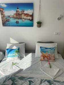 a bedroom with a white bed with a picture on the wall at One minute to the beach in Becici