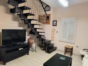 uma sala de estar com uma escada em espiral e uma televisão em Casa El limonero em Sevilha
