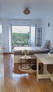 Zimmer mit einem Bett, einem Tisch und einem Fenster in der Unterkunft Petite touche douceur - studio avec parking et terrasse in Suresnes