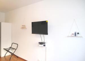 einen Flachbild-TV an einer weißen Wand mit einem Stuhl in der Unterkunft Petite touche douceur - studio avec parking et terrasse in Suresnes