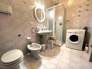 a bathroom with a toilet a sink and a washing machine at L'Angolino di Giò in Pescantina