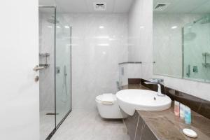 a white bathroom with a sink and a shower at Spacious One Bedroom Apartment in Dubai