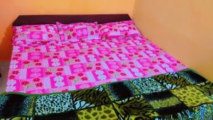 ein Bett mit einer rosa Tagesdecke mit Blumen darauf in der Unterkunft Mahavir Home Stay in Ujjain