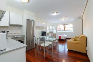 cocina con mesa de cristal y sofá en Luminoso ático para dos by CABANA Rentals, en Vigo