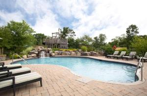 a swimming pool with chairs and a waterfall at Luxury Resort Villa in Muskoka in Gravenhurst