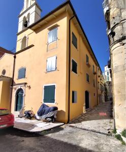 un edificio amarillo con una torre de reloj en una calle en The Monastery Apartment, en Corfú