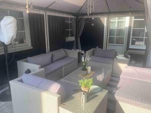 an outdoor patio with couches and a table with at Cozy Stay near Stockholm with Pool and BBQ access in Bro