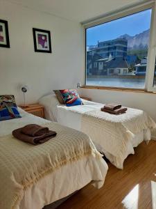 2 Betten in einem Zimmer mit einem großen Fenster in der Unterkunft Lo de Gaston in Ushuaia