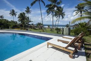 a swimming pool with two lounge chairs and the ocean at Pousada Kaluana in Barra Grande