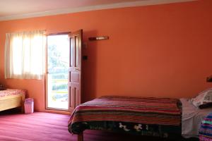 ein Schlafzimmer mit einer orangefarbenen Wand mit einem Bett und einer offenen Tür in der Unterkunft BUNKBEDS Island Amantani in Ocosuyo