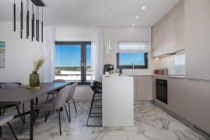 a kitchen and dining room with a table and chairs at HADRIE LUXURY RESORT AND VILLAS PENTHOUSE de in Malinska