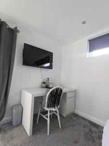 a room with a desk with a tv and a chair at Room in Detached Annex in Cantley