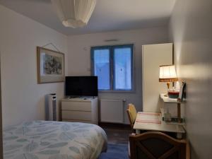 Dormitorio con cama, escritorio y TV en 1 Chambre pour 2 dans une maison "Chez l'habitant", en Quincy-Voisins