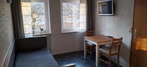 a small table and chairs in a room with windows at Ferienwohnung Clauss in Zwiefalten