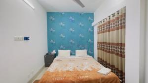 1 dormitorio con cama y pared azul en Chittagong Hotel & Apartment Service, en Dhaka
