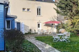 un patio con tavolo, sedie e ombrellone di Maison spacieuse 50 m de la plage a Ouistreham