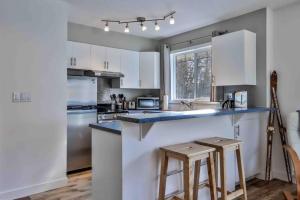 a kitchen with white cabinets and a counter with stools at Big Mountain Views - 2-story Corner Unit in Canmore