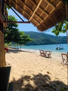 a beach with two chairs and a boat in the water at Camping Mill Off Adventure in Paraty