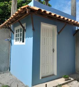 ein blaues Haus mit einer weißen Tür und einem Fenster in der Unterkunft Pousada Raio de Sol - Ilha de Itaparica- Catu á 150 m da praia in Vera Cruz de Itaparica