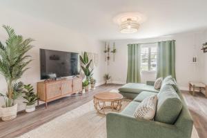 a living room with a green couch and a tv at 10 Mins to Beach - 2BR Private Pool + Spa + Grill in Vero Beach