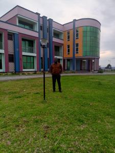 a man standing in a field in front of a building at Panorama Kyenjojo Hotel in Kyenjojo