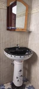 bagno con specchio e lavandino bianco e nero di Panorama Kyenjojo Hotel a Kyenjojo