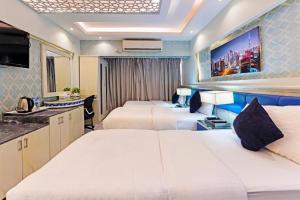 a hotel room with three beds and a tv at Trans World Hotel in Dubai