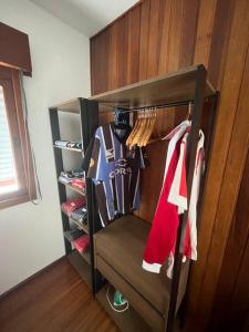 a closet with a rack with jerseys and shoes at Studio Grenal - JK Bem Localizado in Porto Alegre