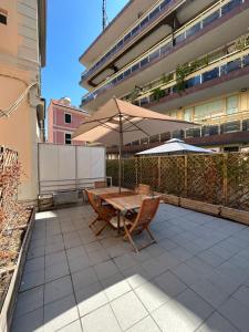 un patio con sombrilla, mesa y sillas en Da Mariella case vacanze con terrazzo, en San Remo