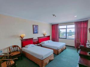 a hotel room with two beds and a window at PIA Hotel Bandung in Bandung