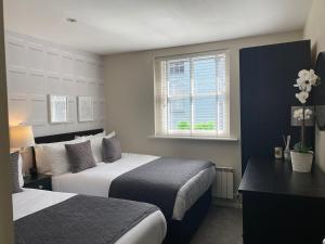 a hotel room with two beds and a window at The Hamptons by Brighton Holiday Lets in Brighton & Hove