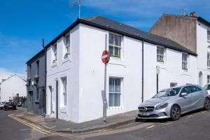 a white building with a car parked in front of it at The Hamptons by Brighton Holiday Lets in Brighton & Hove