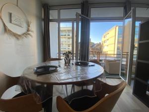 a dining room table with chairs and a large window at Un extérieur en ville in Cherbourg en Cotentin